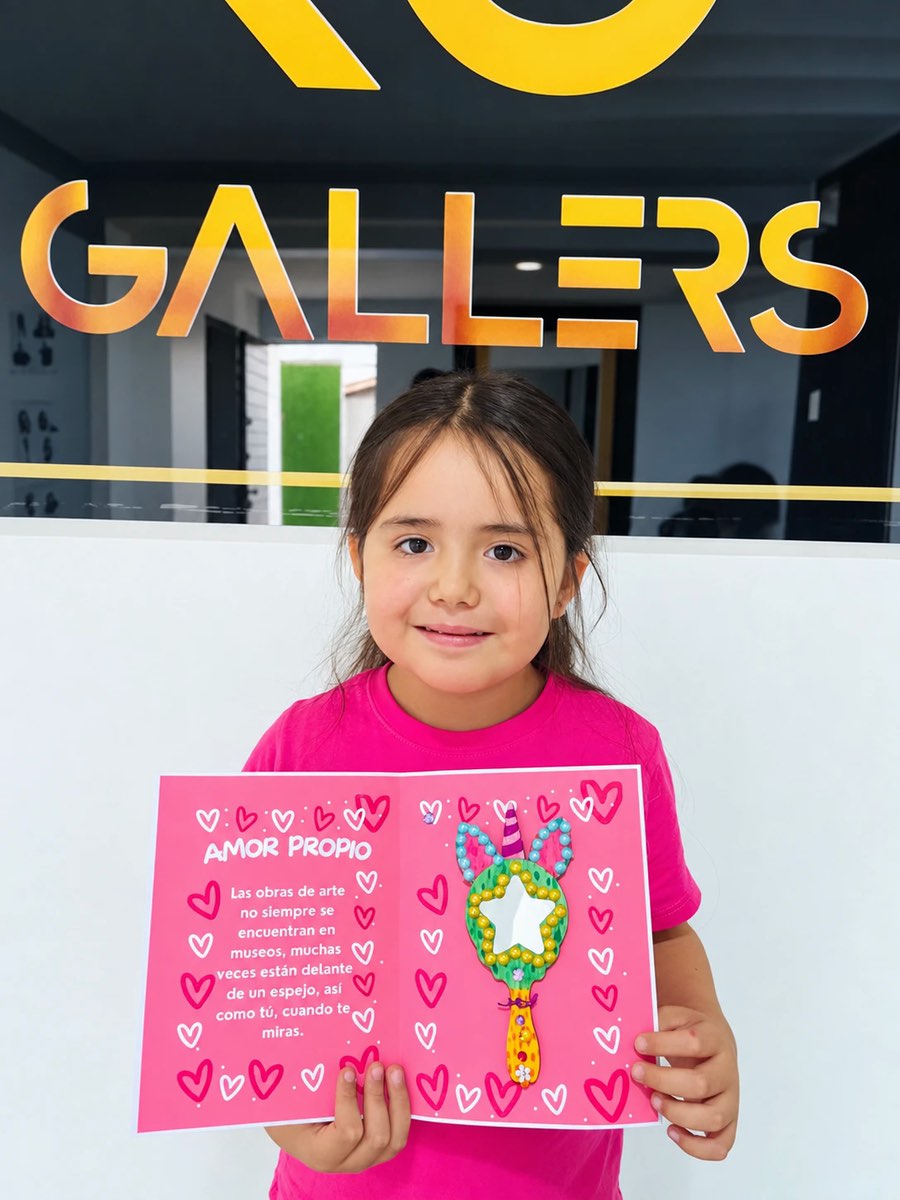 Niña de Kids mostrando la tarjeta del taller de amor propio frente al logo de Gallers